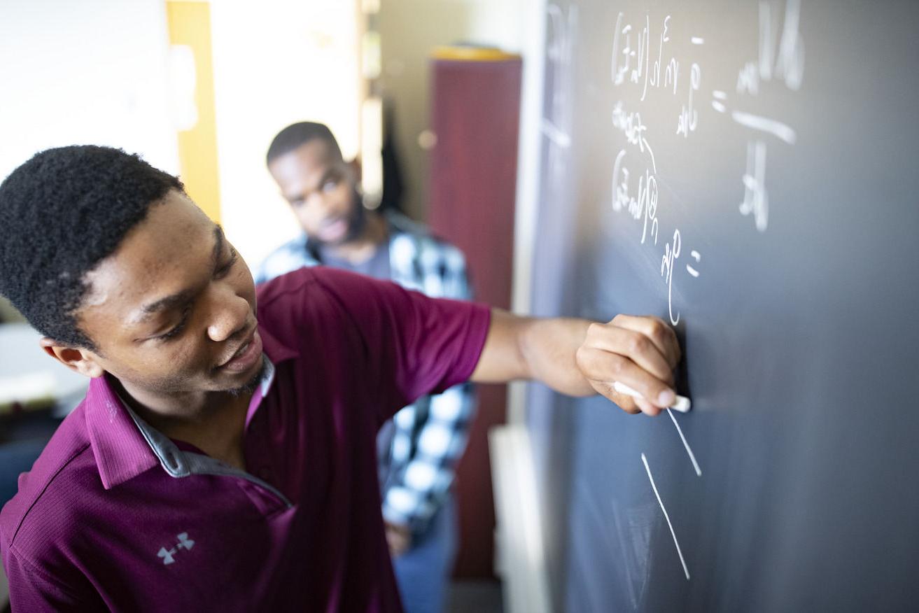 一个学生在黑板上写数学方程式的图像.